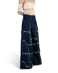 Three-quarter view of Faultline denim showing its wide-leg profile, raw-edge panel openings and printed fabric underlayers.